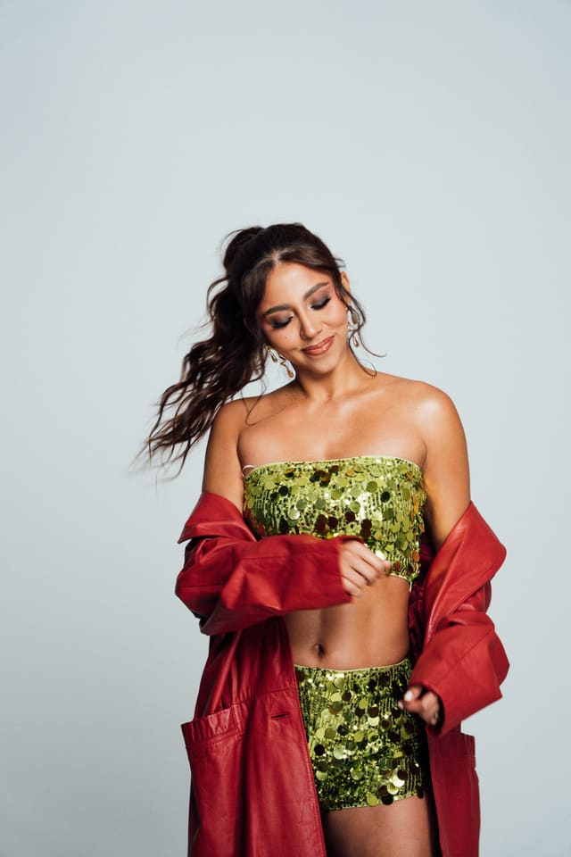 Naomi V · De pie, con lentejuelas verdes y chaqueta roja